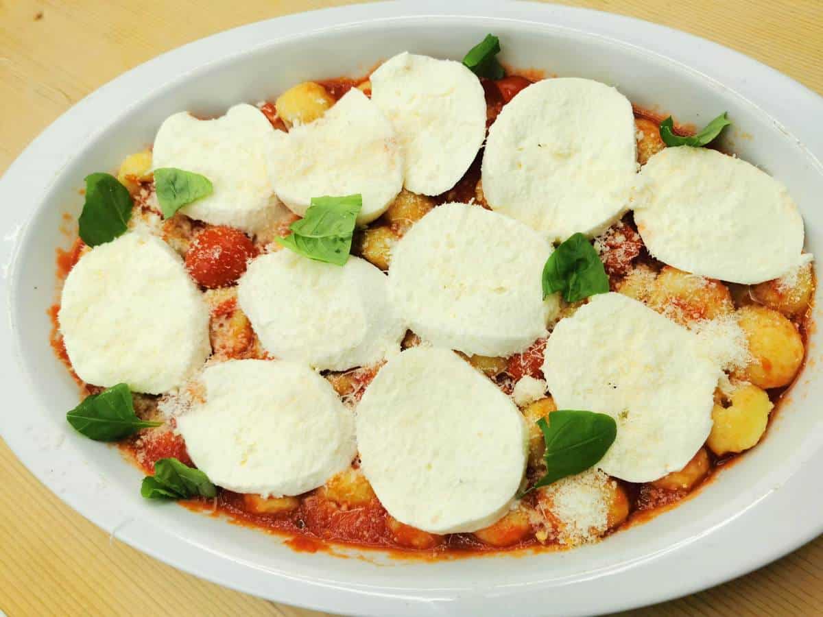 Slices of fresh mozzarella, grated parmigiano reggiano and basil leaves on top of the gnocchi alla sorrentina.