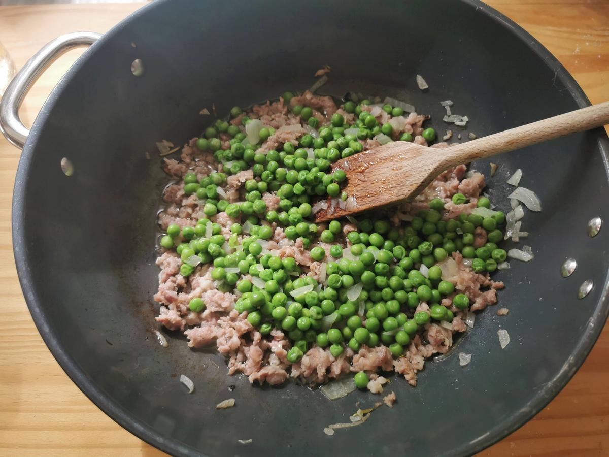 Cooked peas added to sausage and onion cooking in skillet.