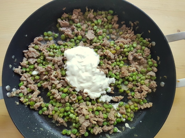 heavy cream added to sausage meat, peas and onions in skillet