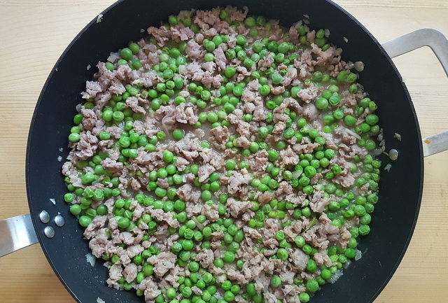 sausage meat, peas and onions cooking in skillet