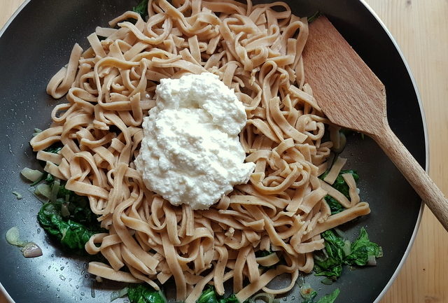 hazelnut pasta with spinach and ricotta cream in frying pan