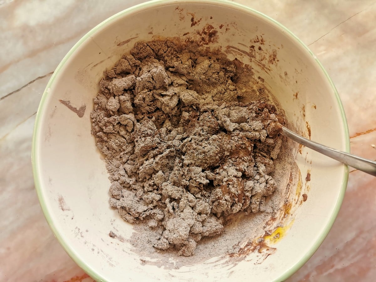 Chocolate ravioli dough starting to form as eggs are mixed with the flour and cocoa powder.