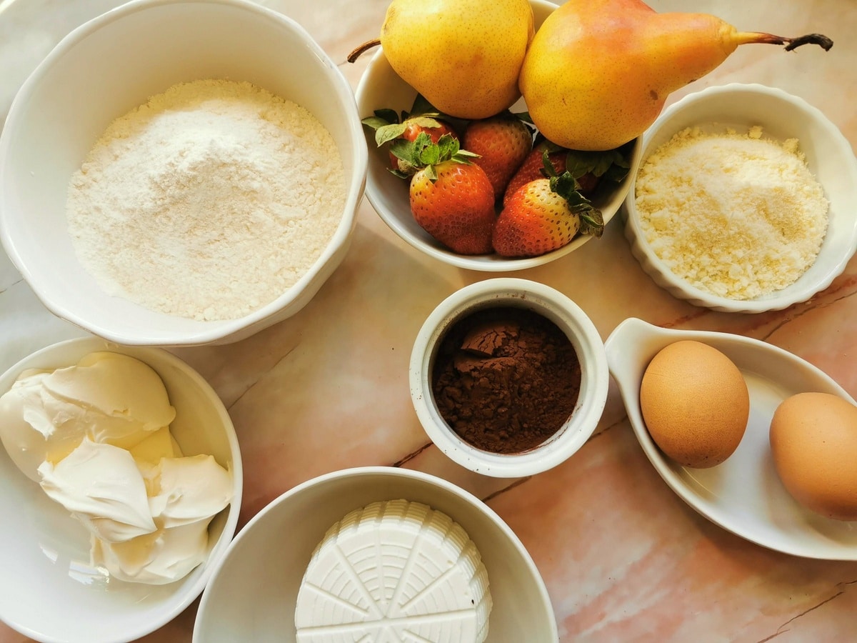 Ingredients for chocolate ravioli and mascarpone cream with strawberries on marble work top.