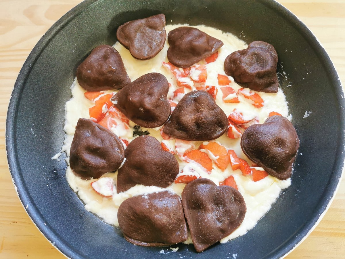 Heart-shaped chocolate ravioli in pan with mascarpone and strawberry sauce.