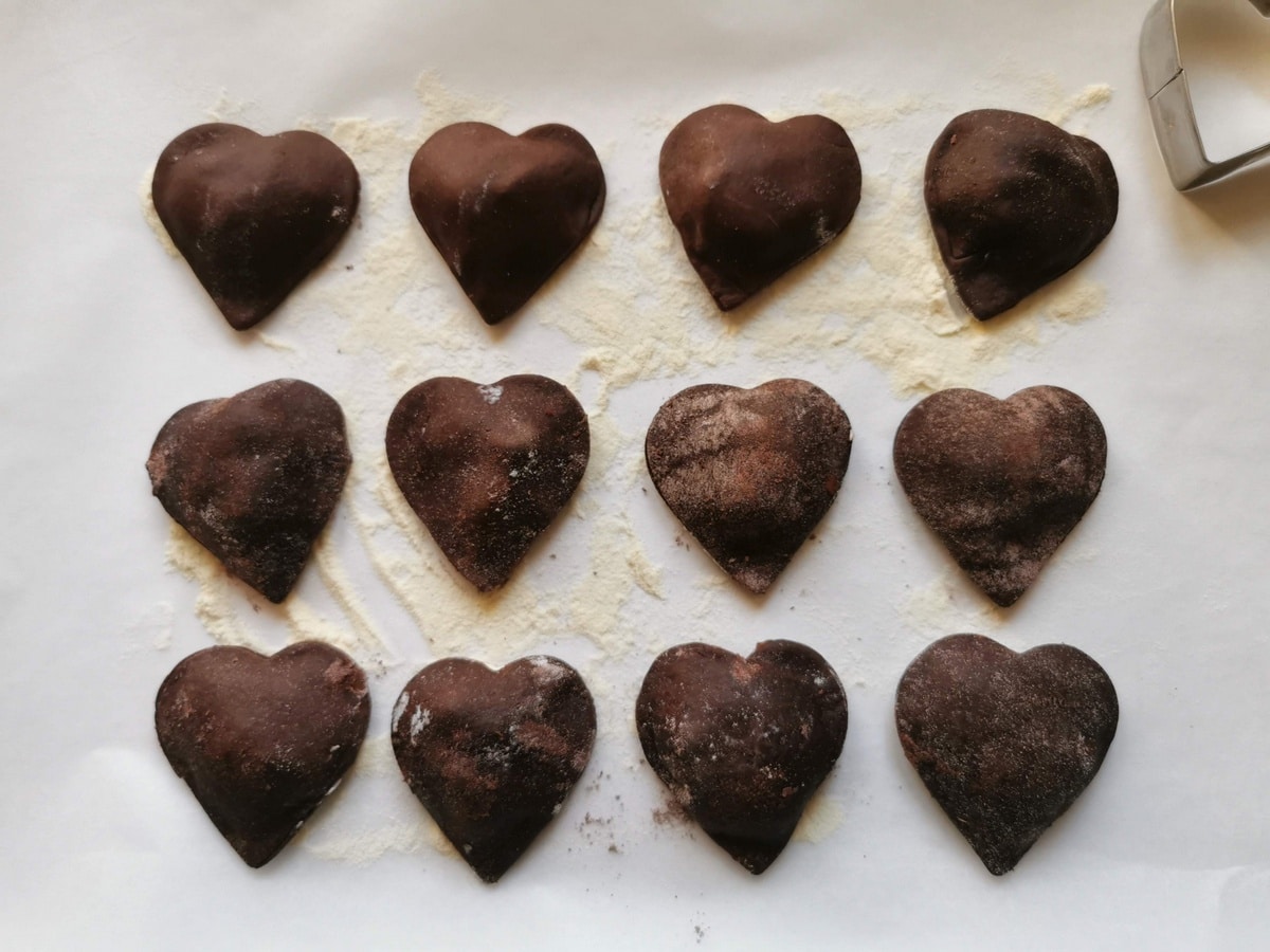 12 heart-shaped chocolate raviolis on a flour dusted white tray.