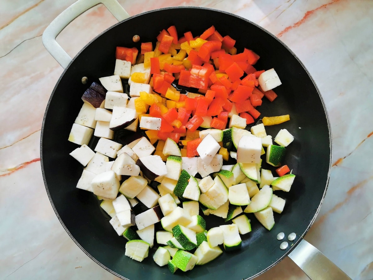 cubed eggplant, zucchini and sweet peppers in skillet with olive oil and crushed garlic