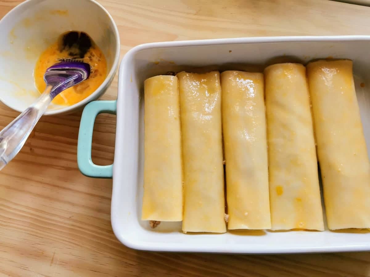 ready to cook homemade cannelloni in oven dish with bowl of egg yolk