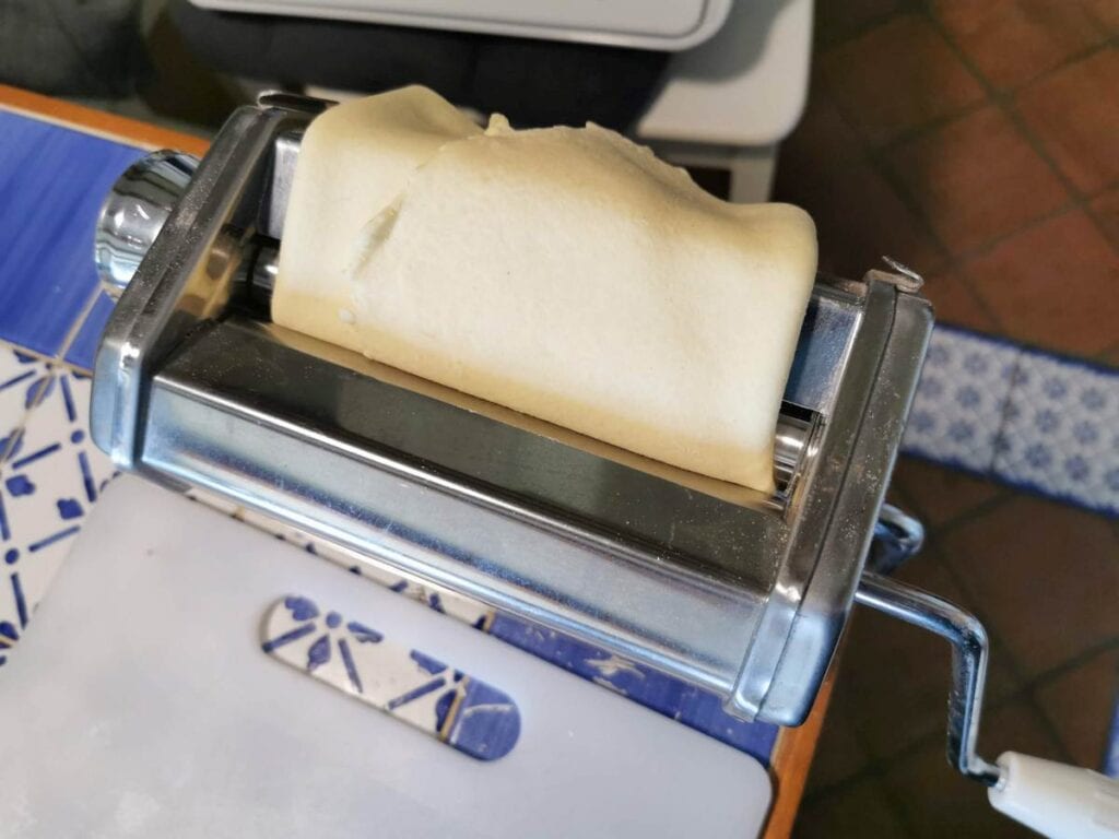 pasta sheet folded in 3 inserted into top of pasta machine