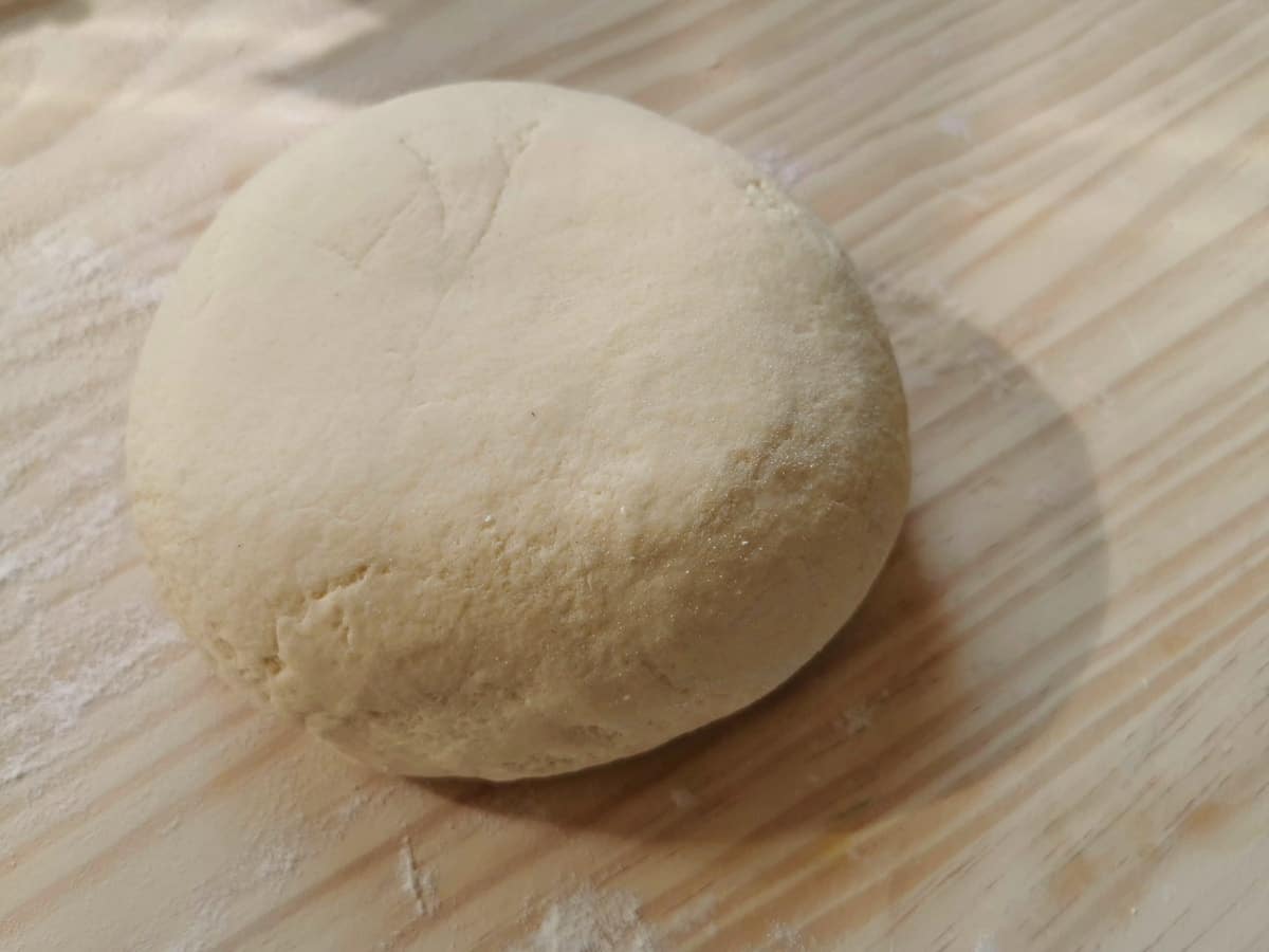 ball of ready cannelloni pasta dough on wooden pastry board.