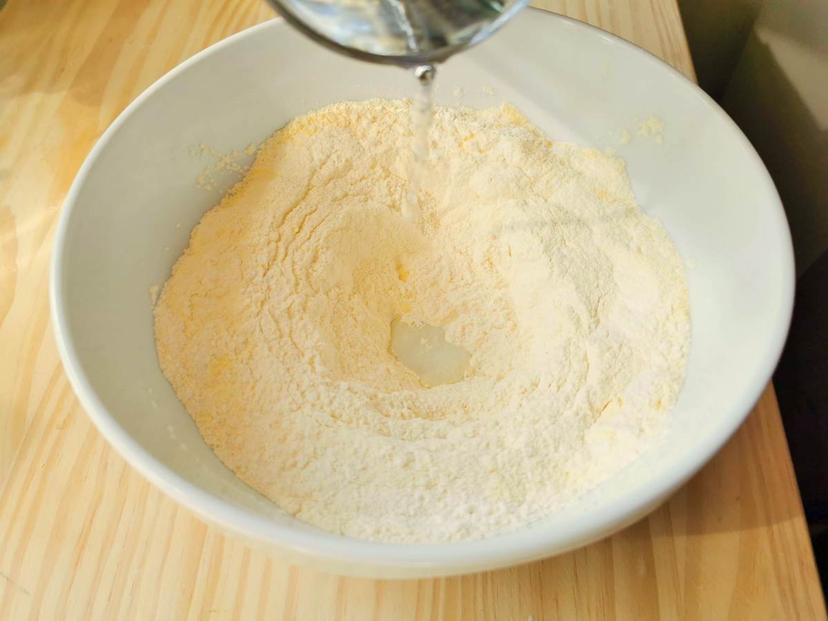 mixed wheat flour and corn flour in white bowl with water added