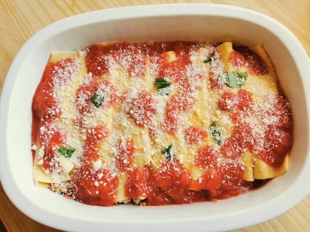 homemade cannelloni with tomato sauce ready to go in oven