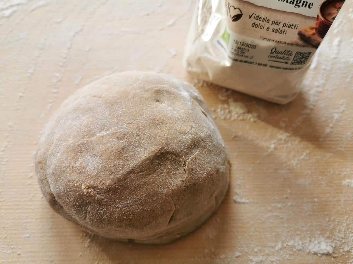 ball of homemade chestnut pasta dough on wooden pastry board