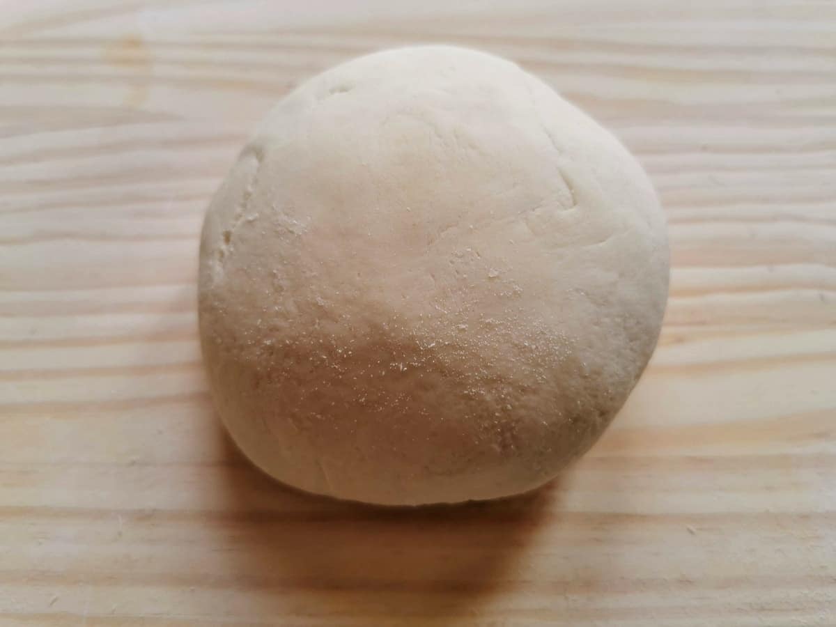 A ball of pasta dough on pastry board.