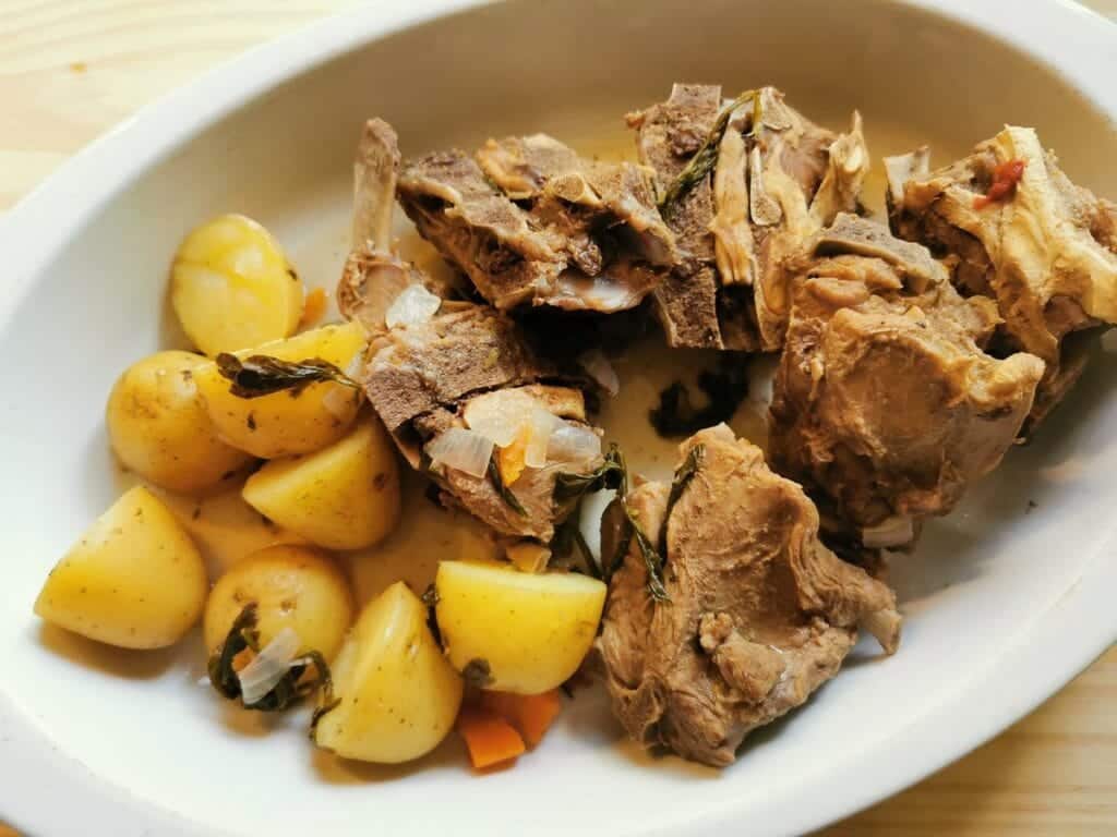 Cooked lamb neck bones and potatoes in a white dish