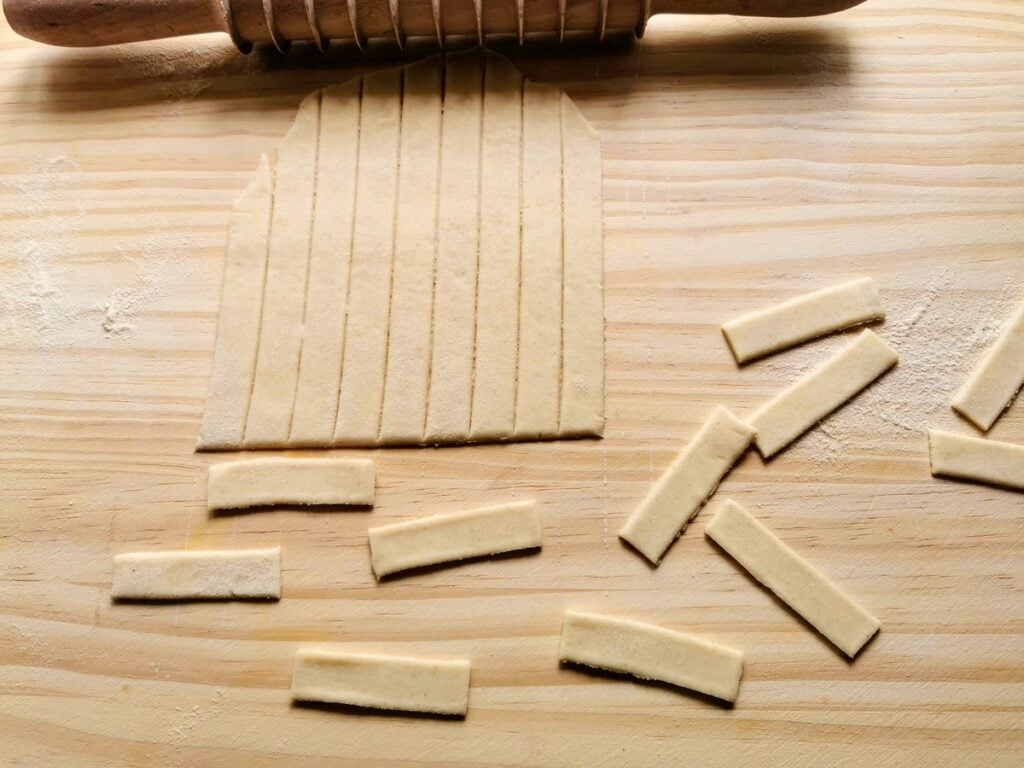 Sheet of rolled out dough cut into strips and small rectangles.