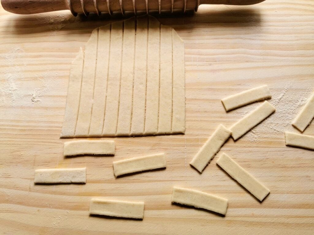 Sheet of rolled out dough cut into strips and small rectangles.