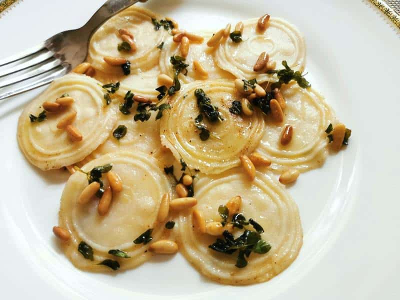 Homemade corzetti pasta with marjoram and pine nuts.