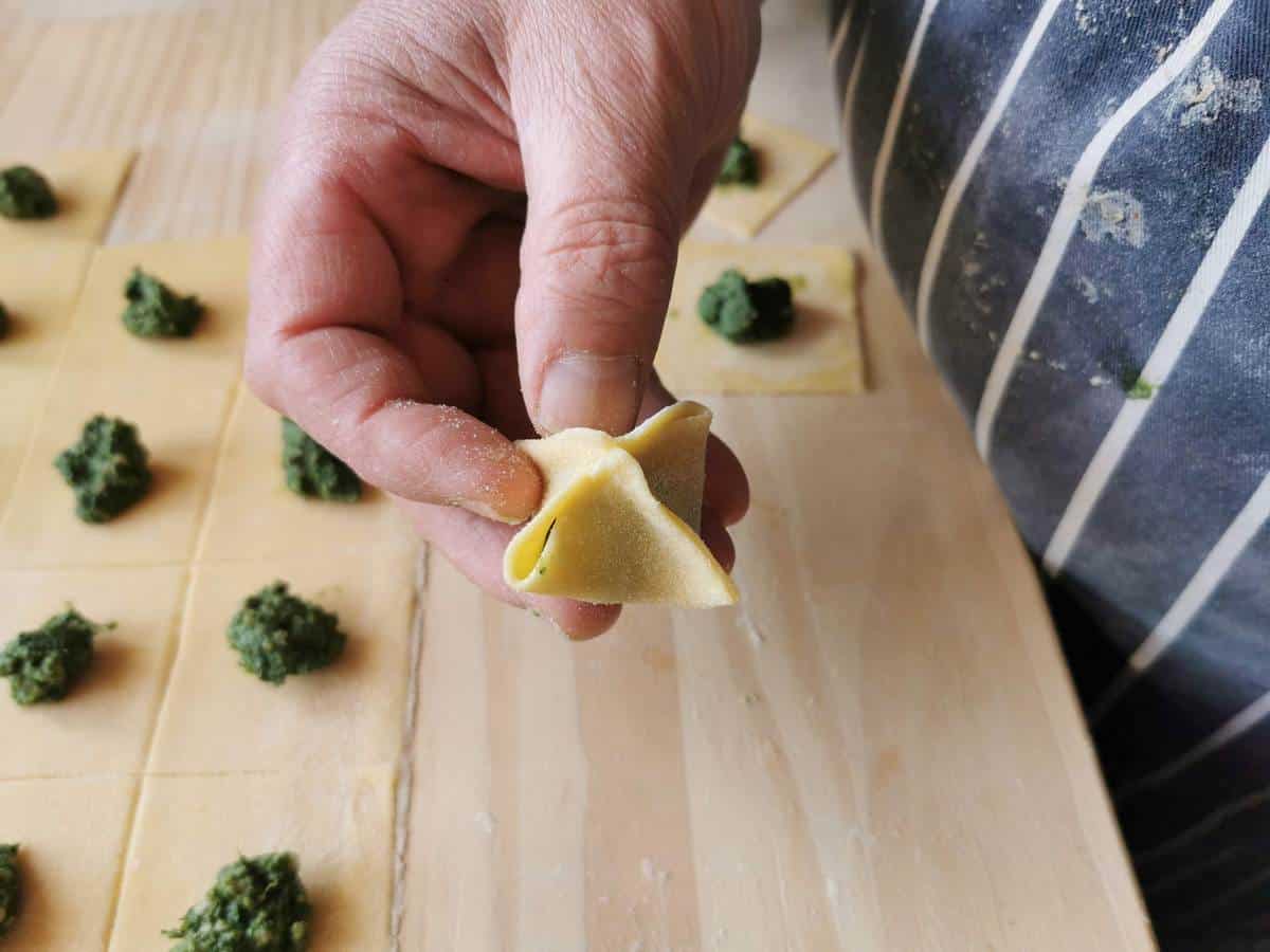 Man holding one piece of freshly made fagottini pasta.