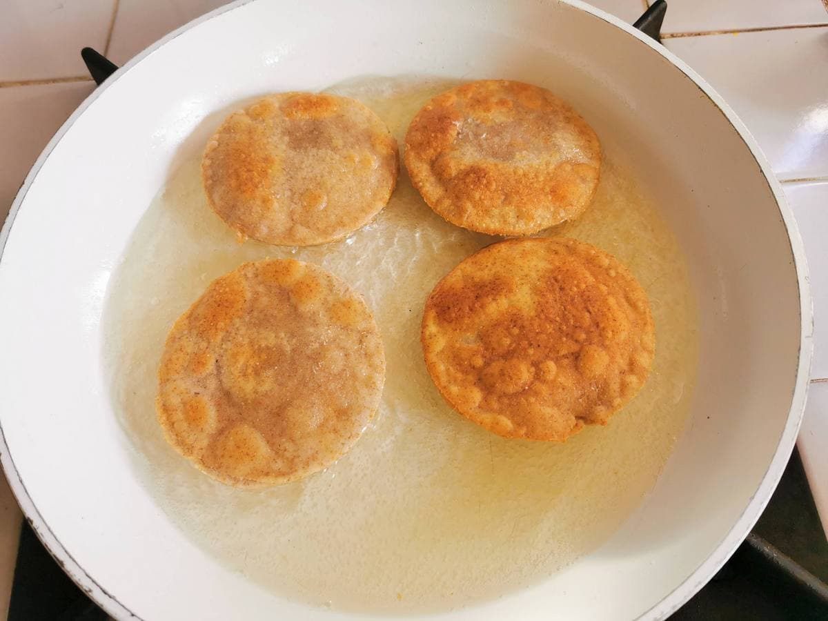 Rye flour ricotta and spinach ravioli frying in oil in frying pan.