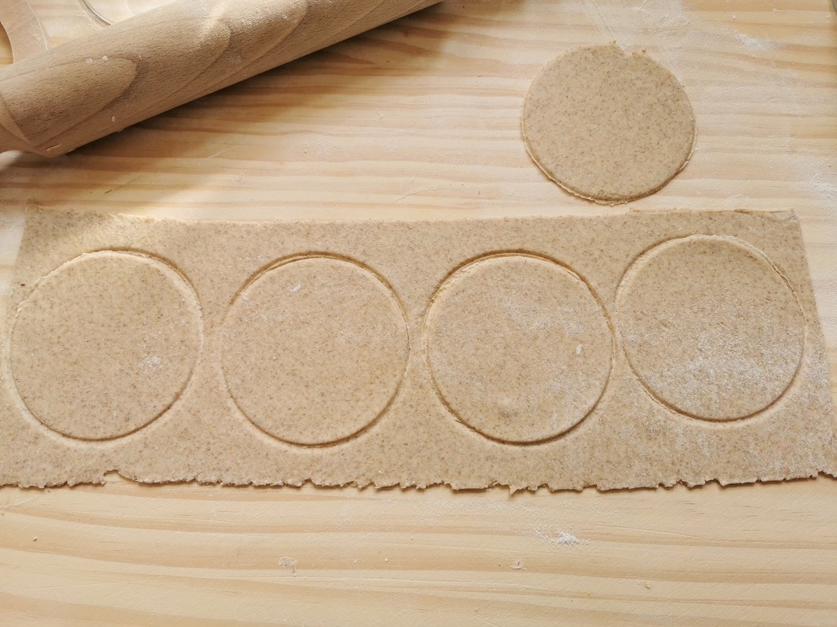 Sheet of rye flour dough with circles cut into it.