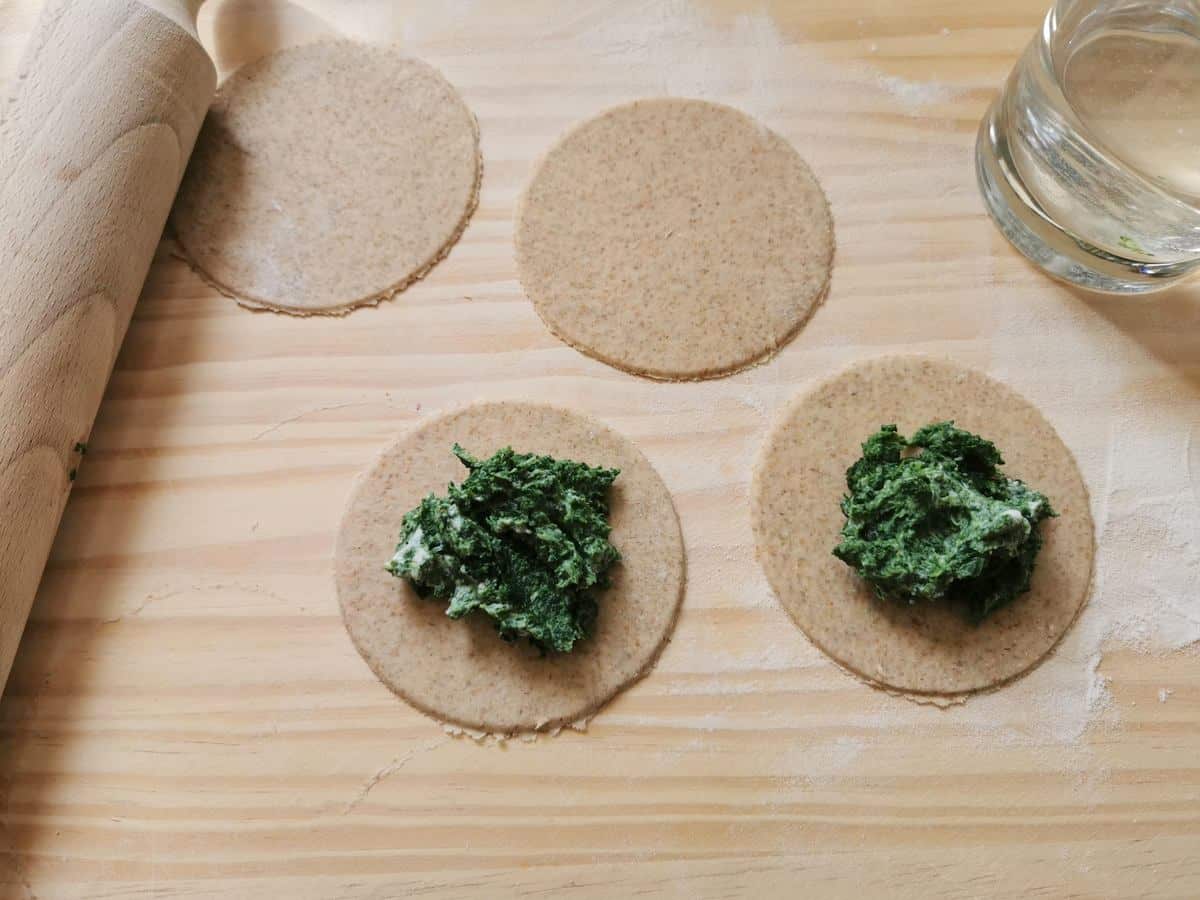 Circles of rye flour dough with spinach filling in the centre.