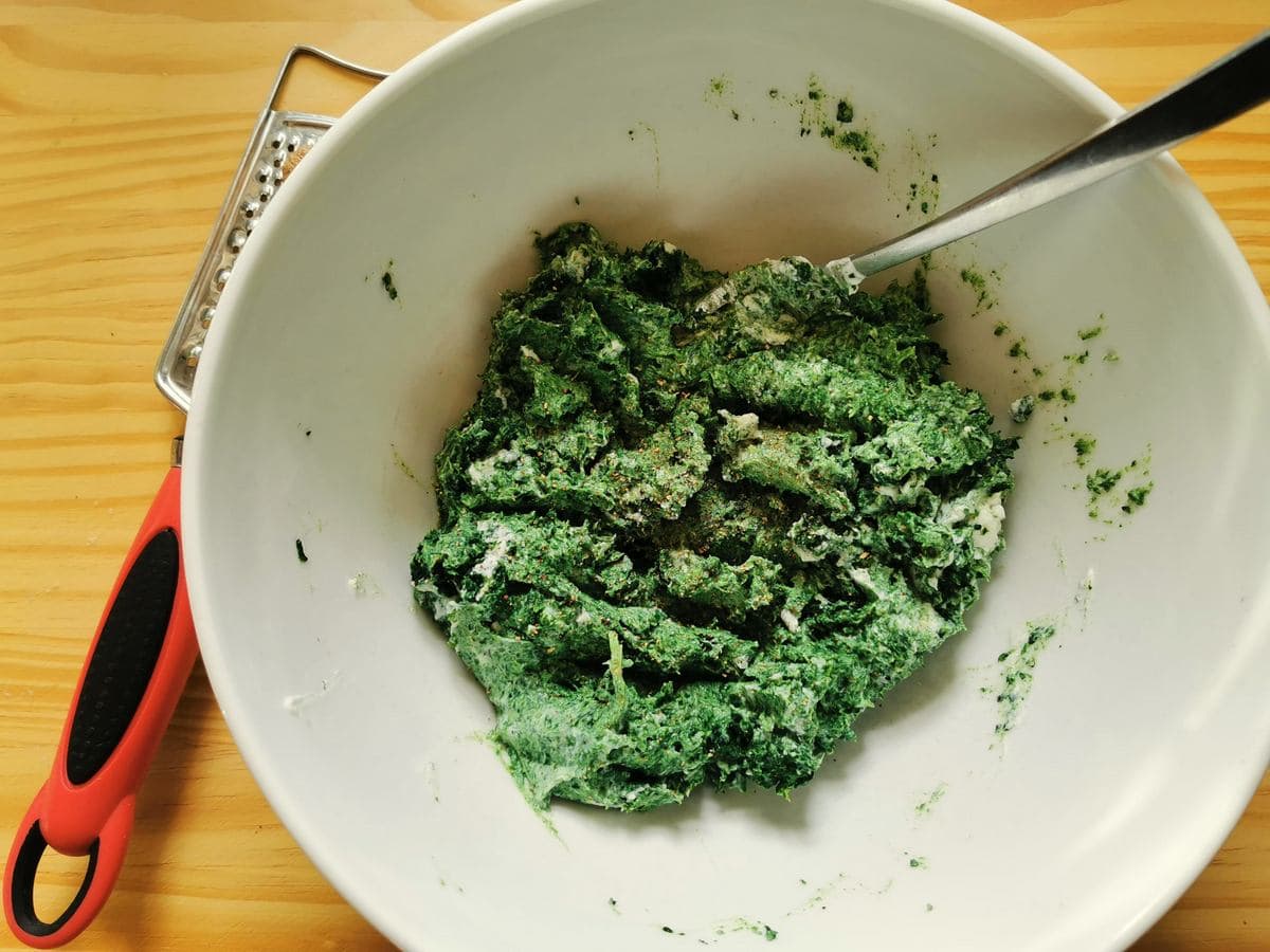 Puréed spinach and ricotta mixed together in white bowl.