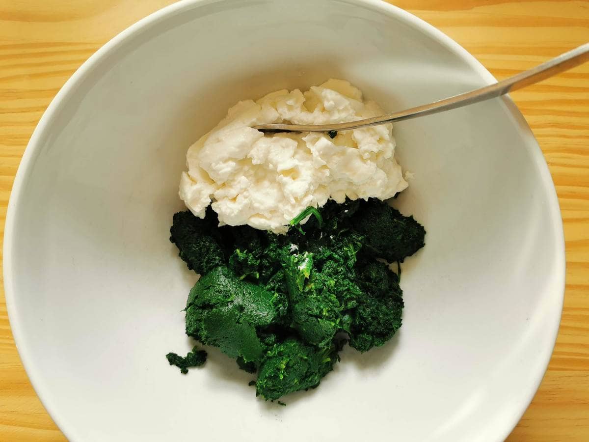 Puréed spinach and fresh ricotta in white bowl.