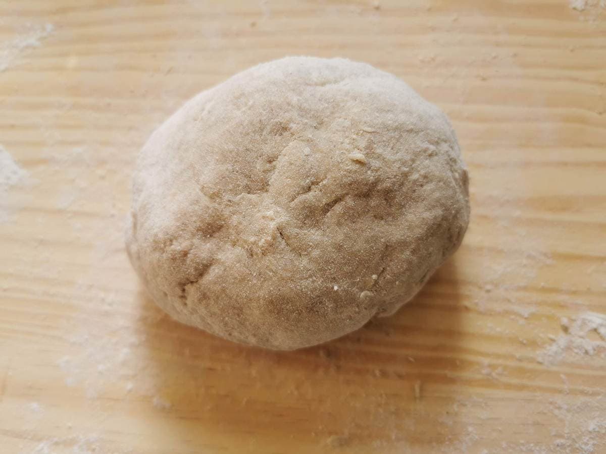 Ball of ready rye flour ravioli dough on wood worktop.