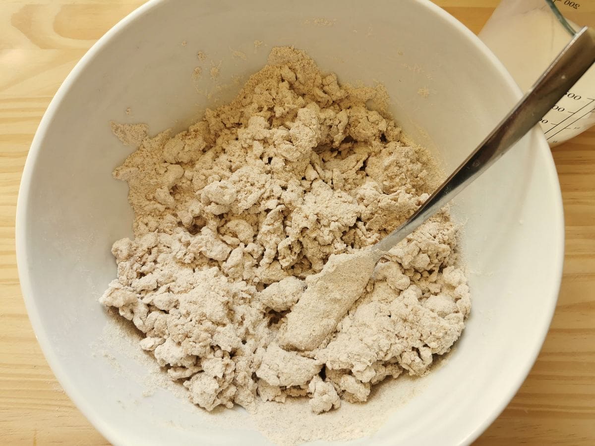 Flour and milk mixed together in white bowl with a fork.