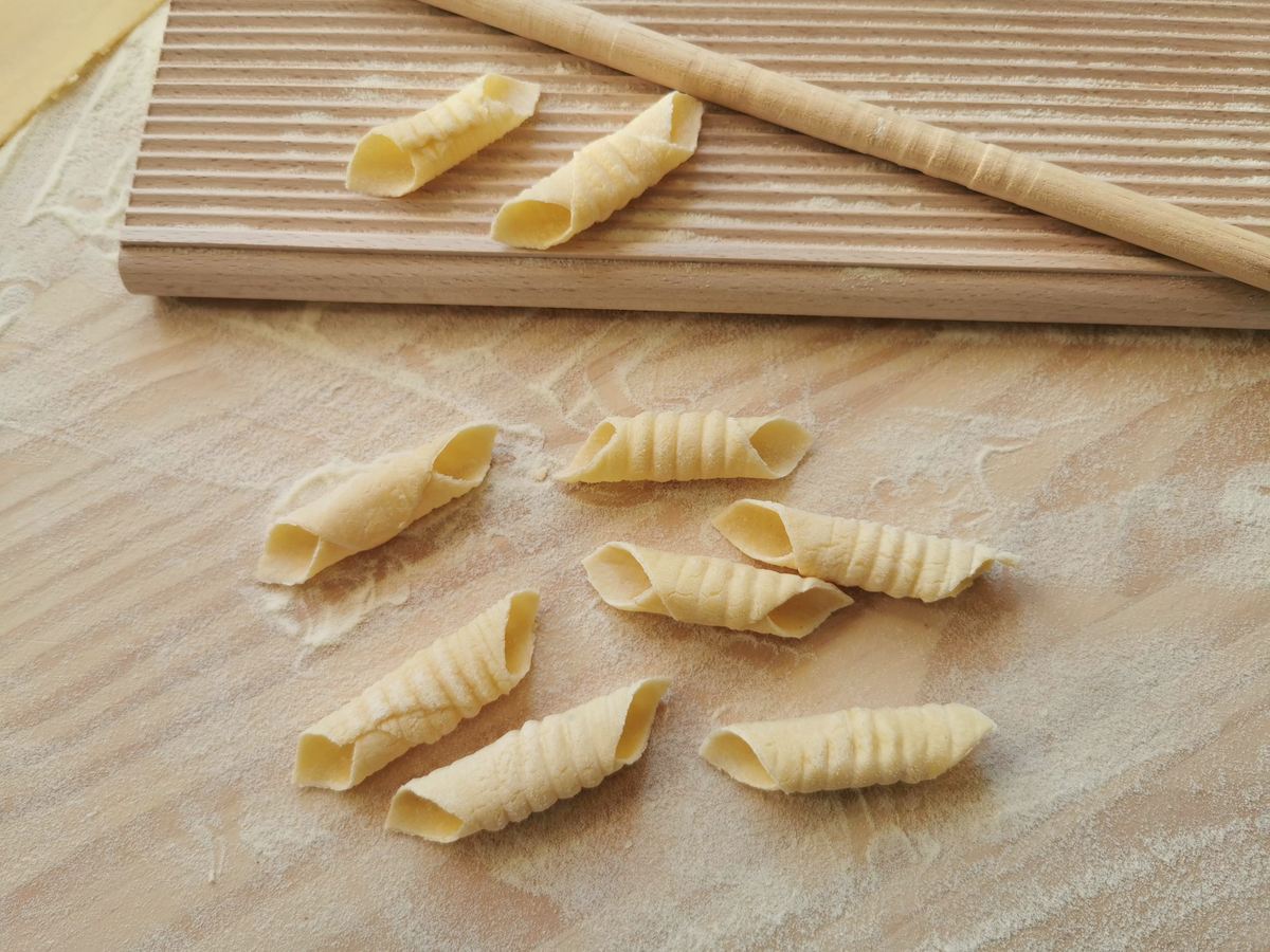 Just made garganelli pasta on flour dusted wood surface next to gnocchi board.
