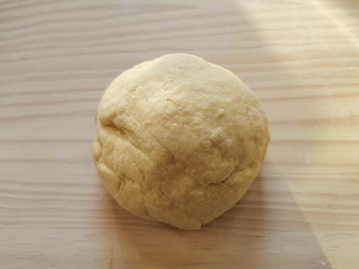 Ball of ready garganelli dough on wood surface.