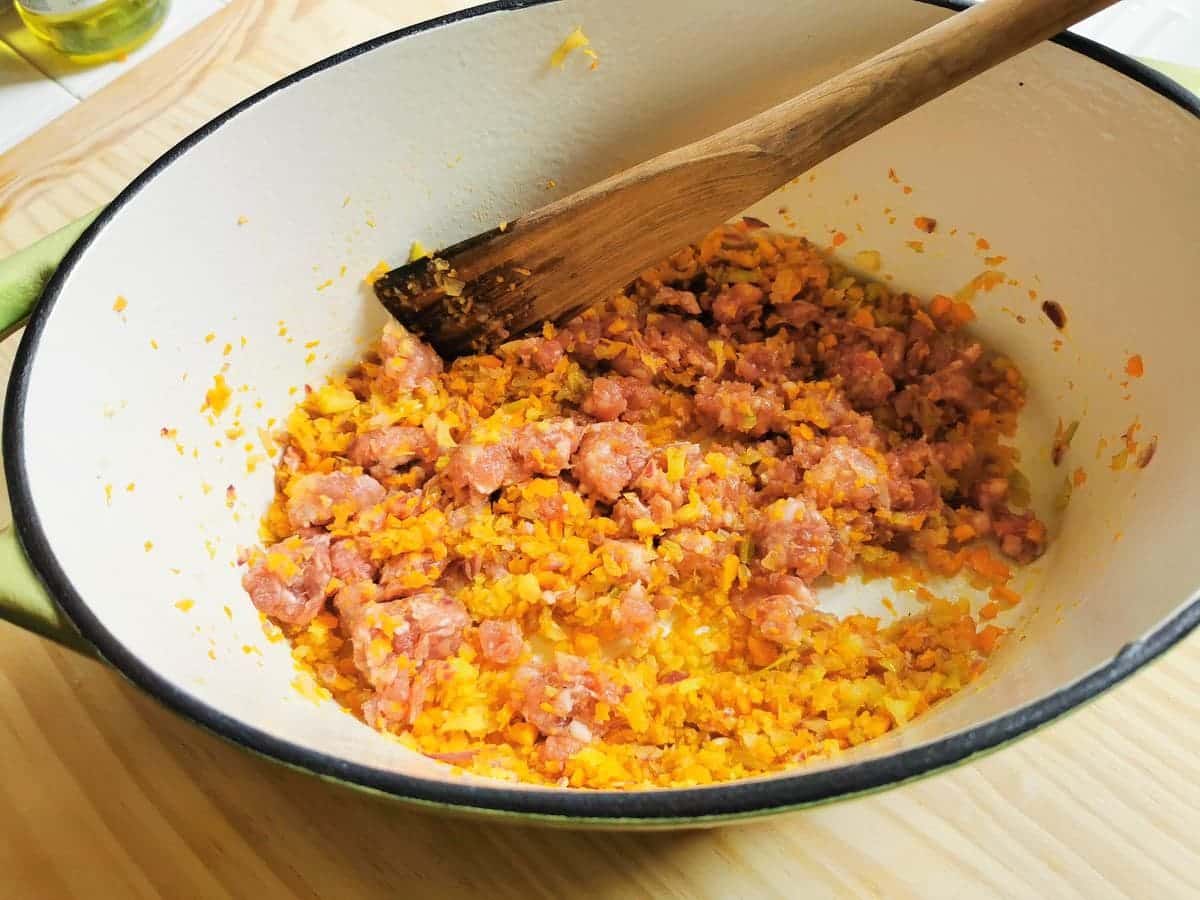 sausage meat added to carrots, onion and celery in Dutch oven