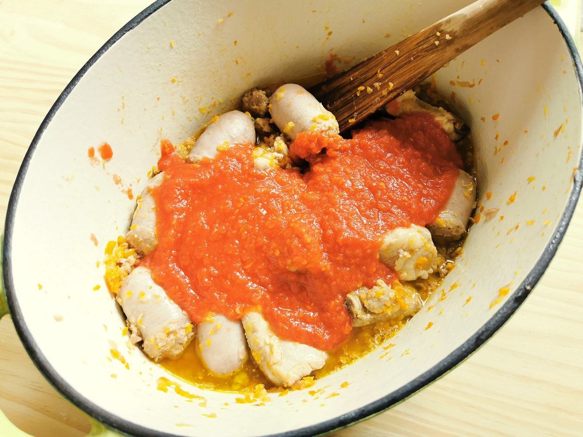 Tomato passata and broth added to sausage and short ribs and vegetables in Dutch oven.