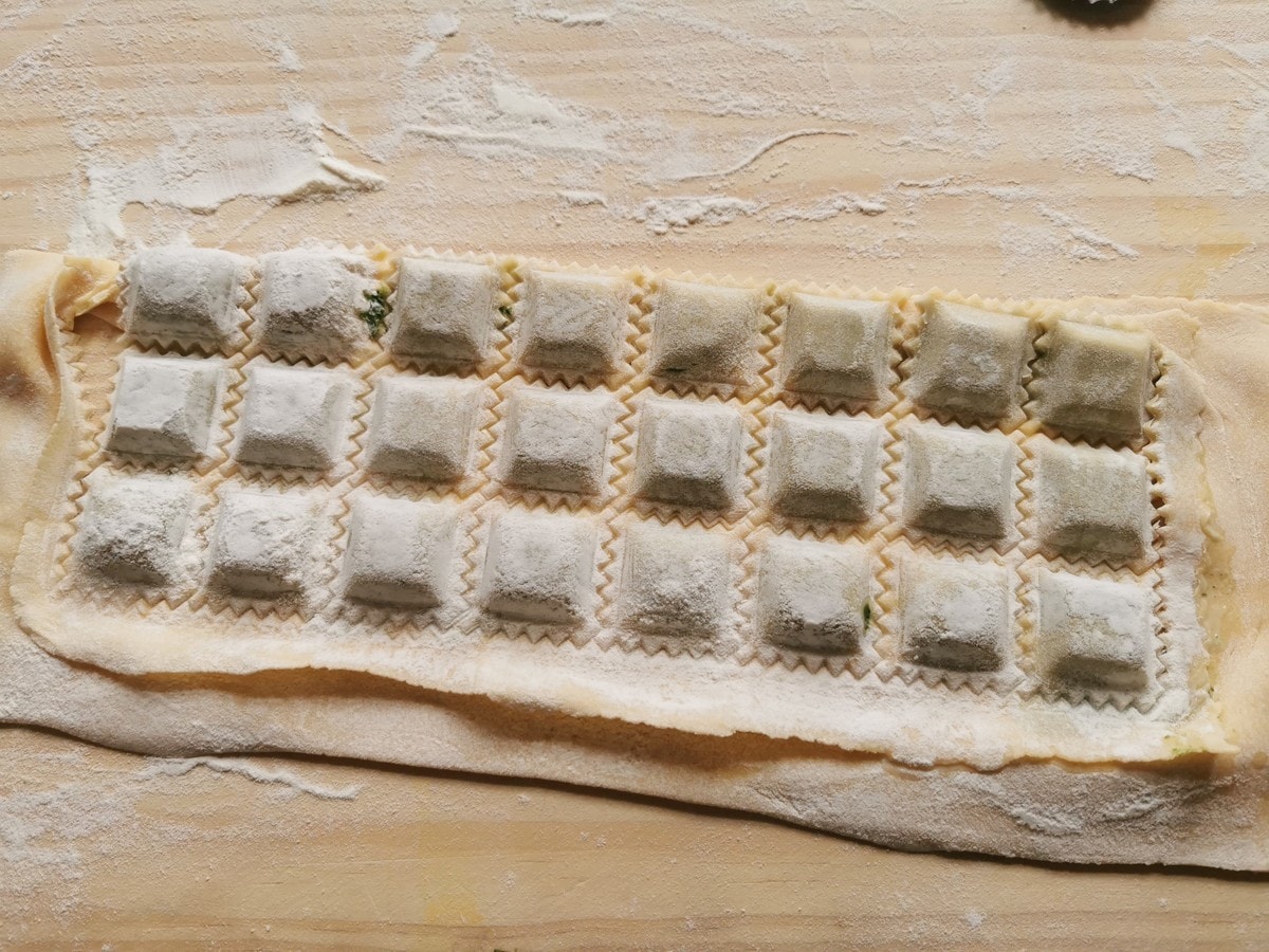 Meat ravioli (agnolotti) out of the ravioli mold but still stuck together.