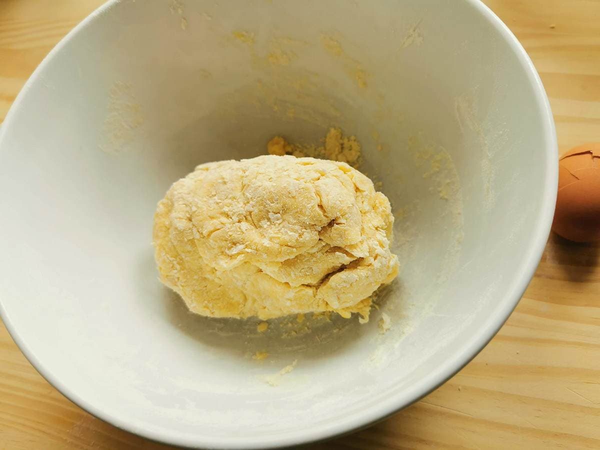Ball of ravioli (agnolotti) dough in white bowl.