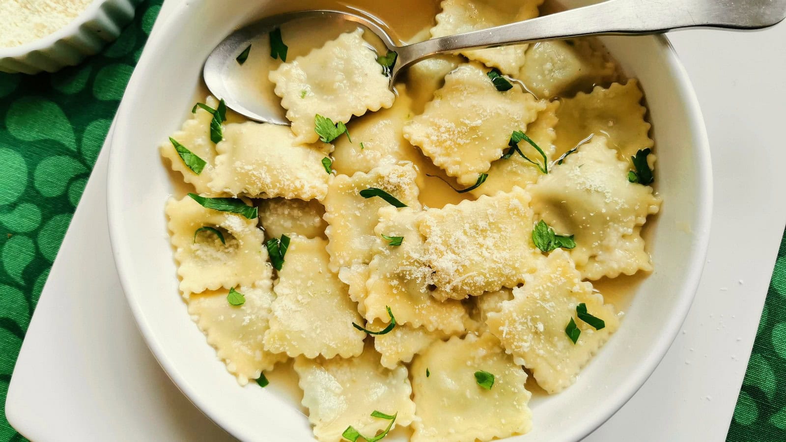 Italian homemade meat ravioli in white bowl with broth.