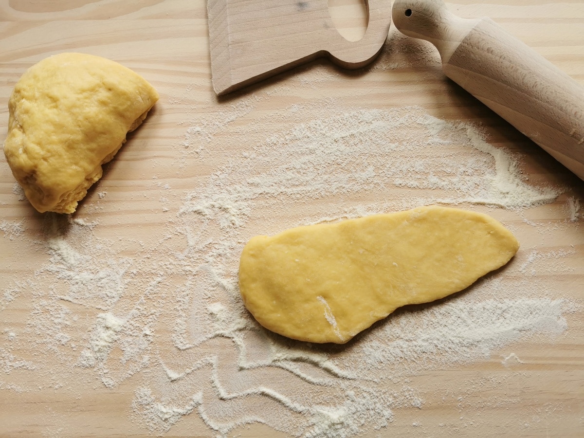 A piece of flattened pasta dough on a flour dusted wood work top.