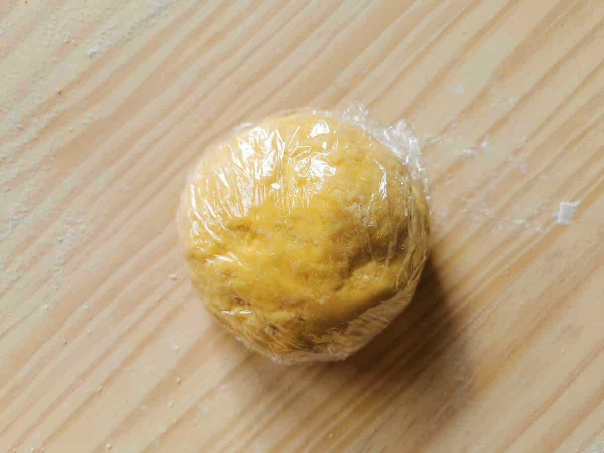 Ball of egg pasta dough wrapped in clingfilm (plastic wrap).