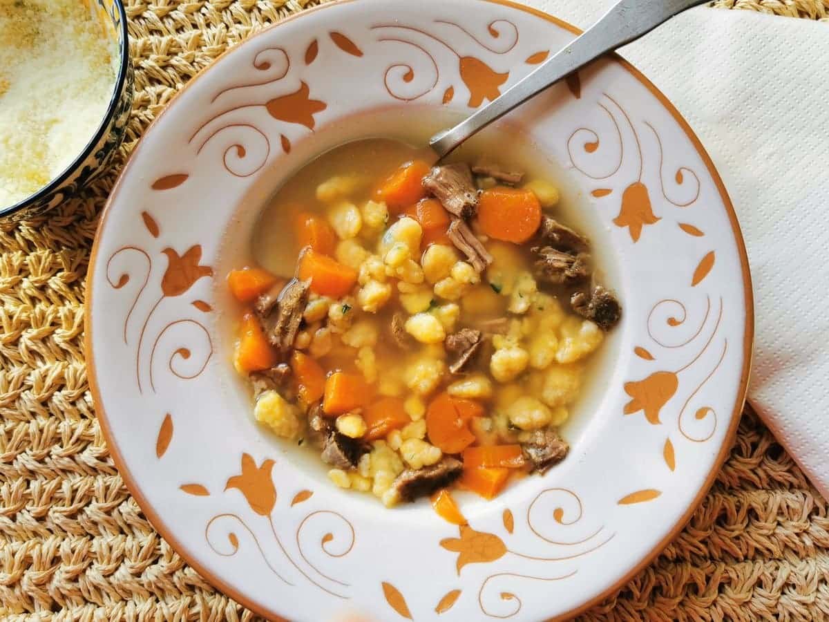 Homemade millefanti pastina in broth in white bowl.