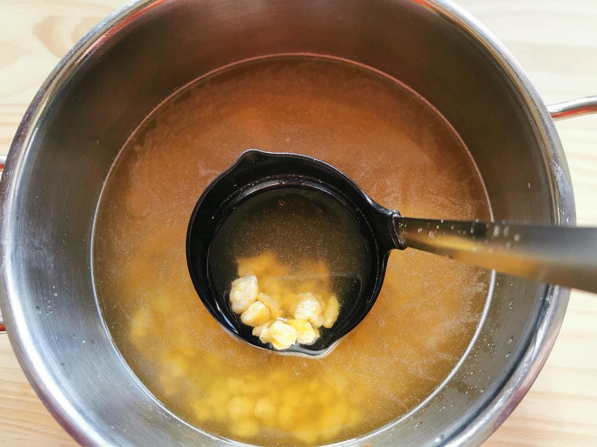 Filtered broth in saucepan with homemade pastina cooking in it.