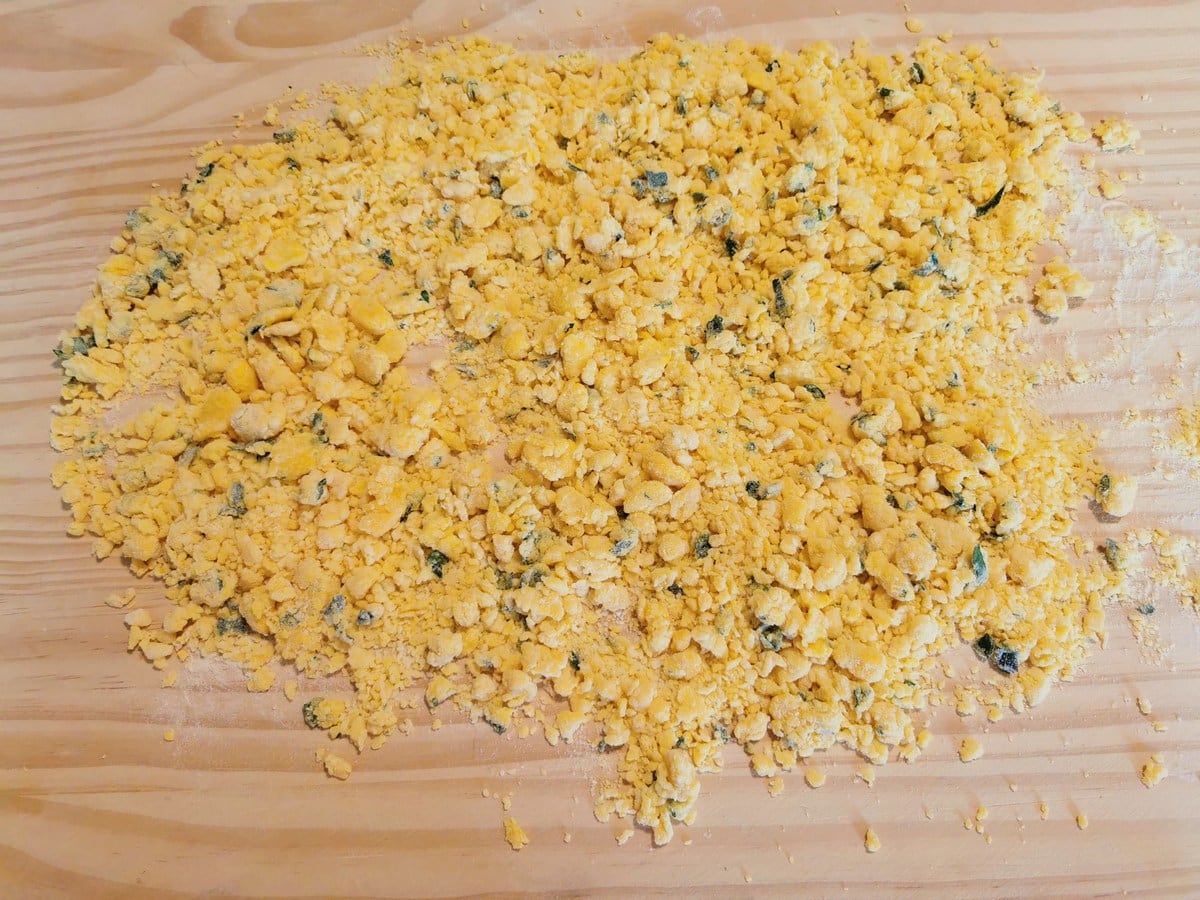 Pieces of millefanti pastina spread out on floured wood board.