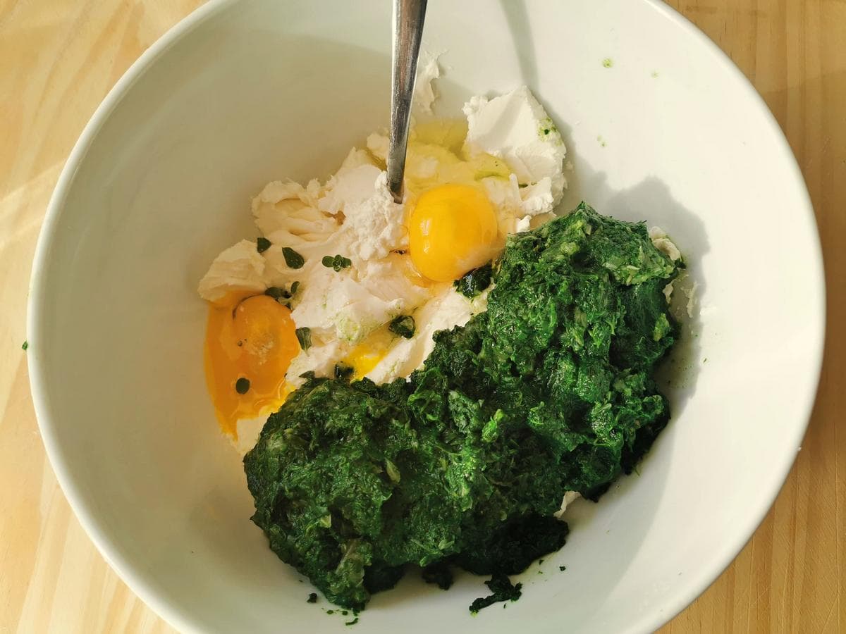 Ricotta, puréed greens, eggs, and herbs in white bowl.