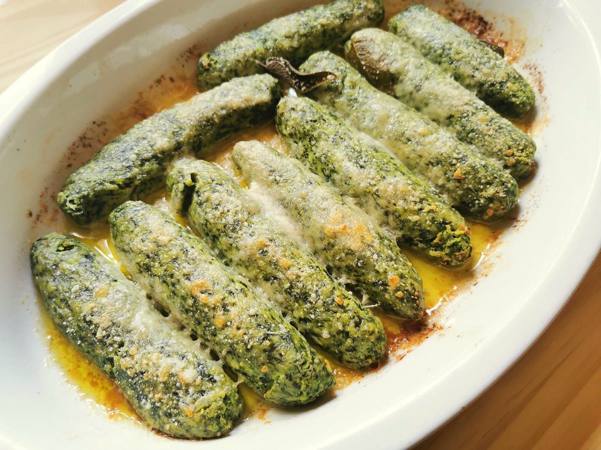 Baked spinach ricotta gnocchi in oval oven dish.