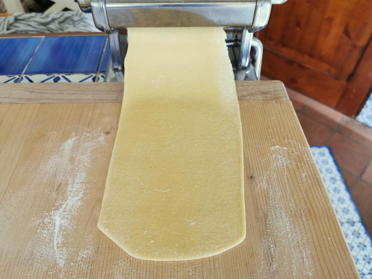 Homemade egg pasta dough sheet in pasta machine.