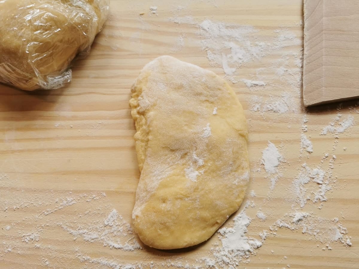 Piece of fresh egg pasta dough on wood pastry board.