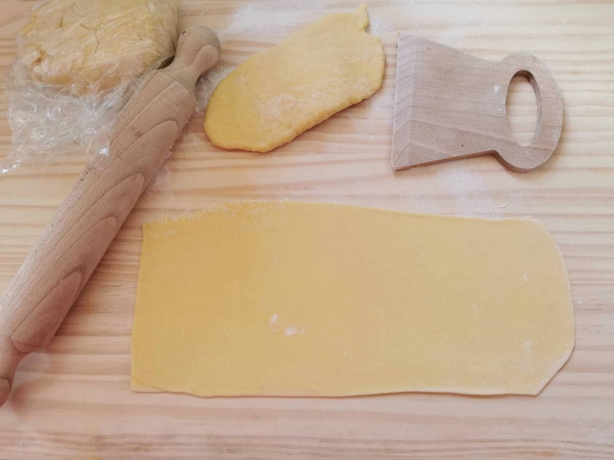 Rectangular sheet of homemade egg pasta dough on wood pastry board.