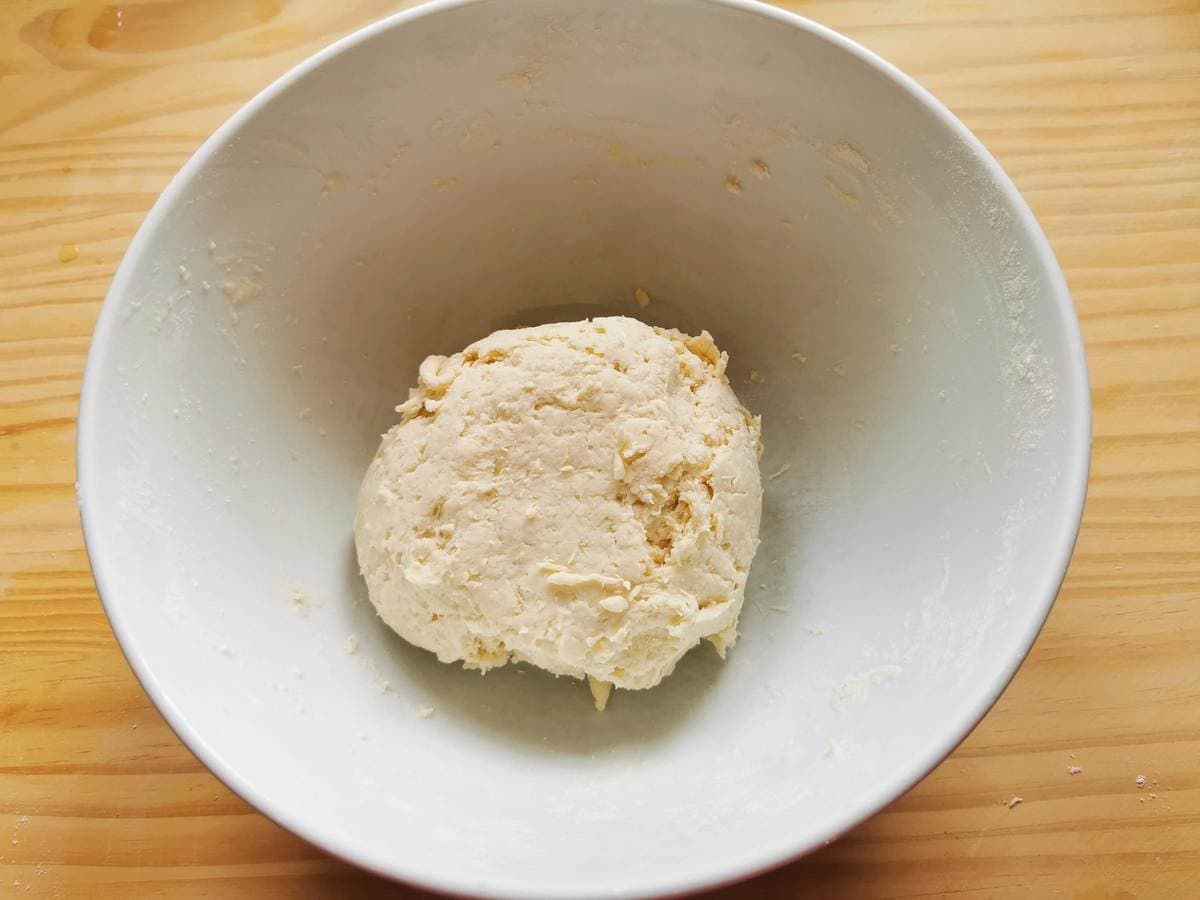 Ball of pasta dough in white bowl.