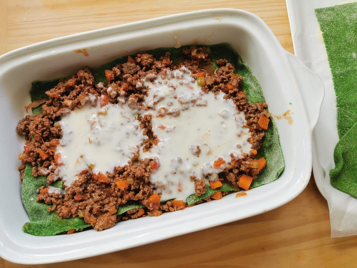 First layers of lasagne al forno in white oven dish.