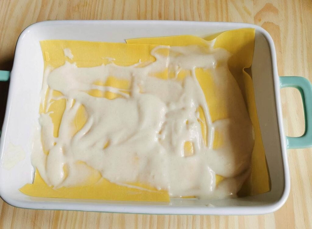 lasagne sheets in oven dish with béchamel spread over them.