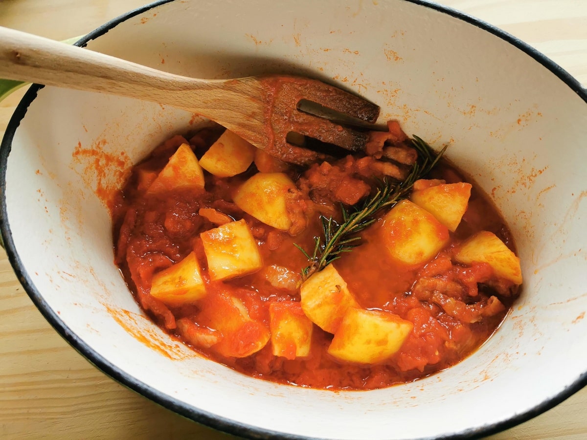 pancetta, tomato passata, potatoes and rosemary cooking in Dutch oven.